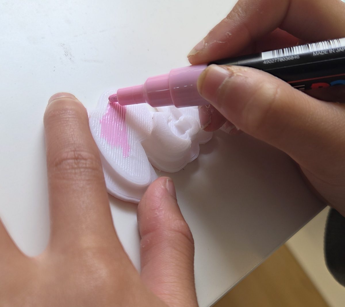 A child colouring a freshly printed bunny with a pink paint pen