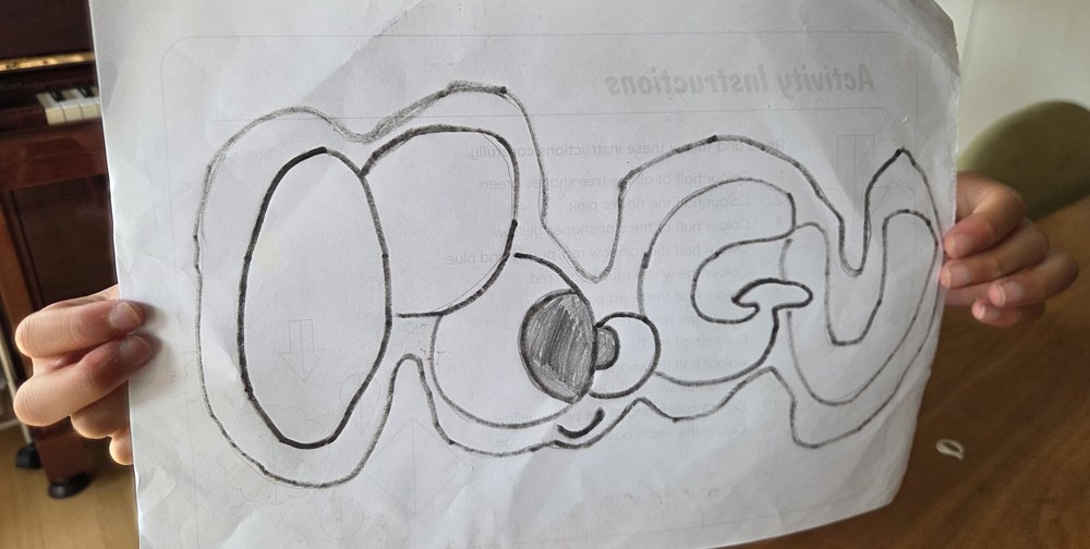 Sophie holding up her pencil drawing of the Poogu logo